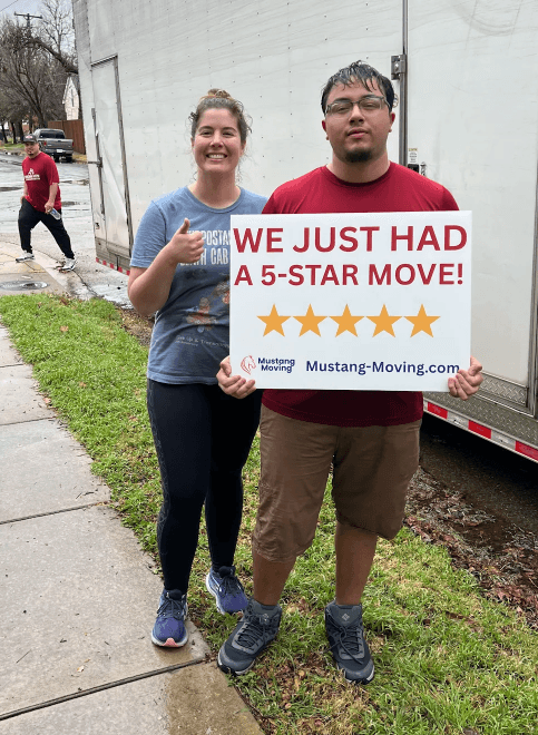 Mustang Moving customers Rachel and Luis with a crew member by the truck on a rainy day.