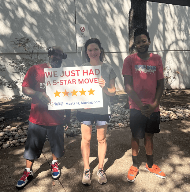 Mustang Moving customers the Harper family with two crew members on a city sidewalk.