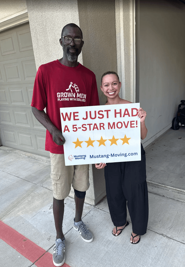 Mustang Moving customer Kayla D. with a crew member outside her garage.